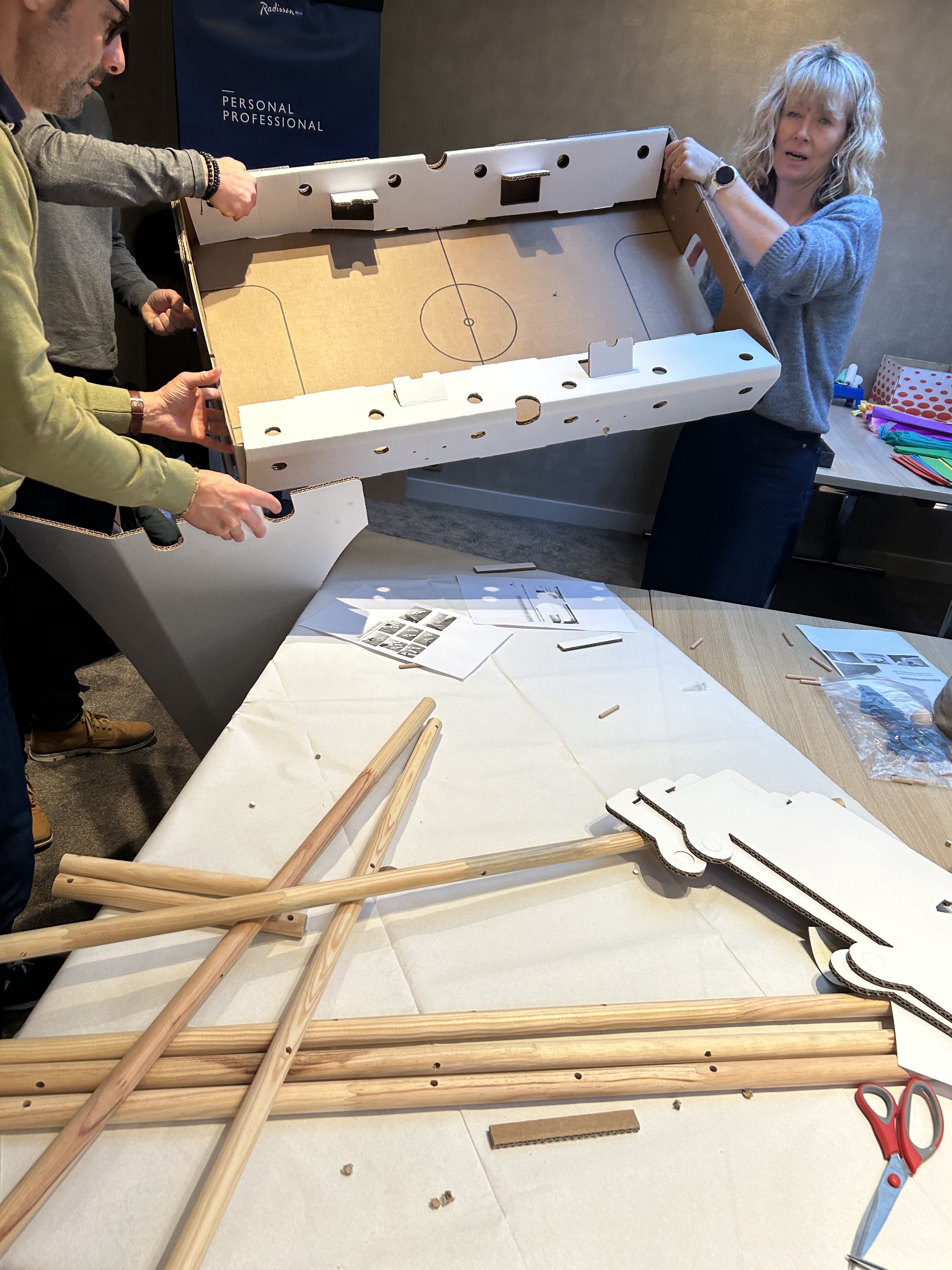 Babyfoot bouwen workshop Luik team assembleert stangen in industriële loft · INNOV'events