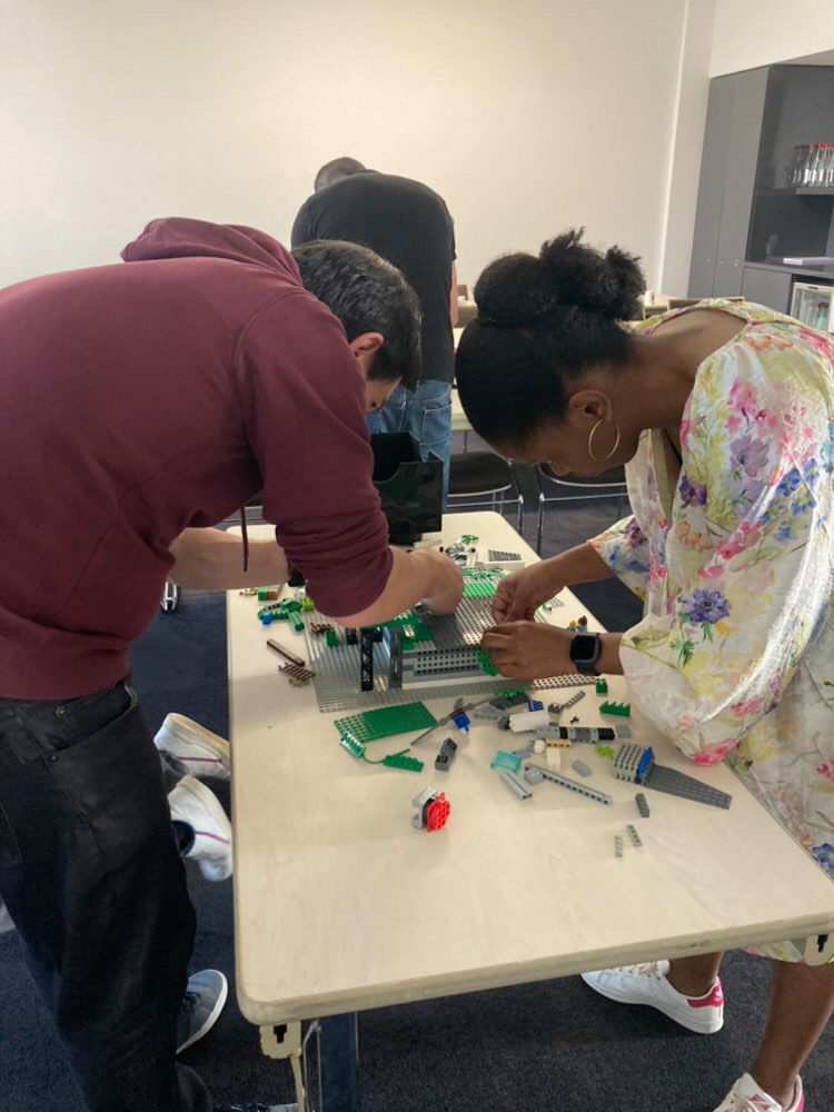 Buitensessie LEGO challenge Luik Maas-oever teams in actie zomerse dag · INNOV'events