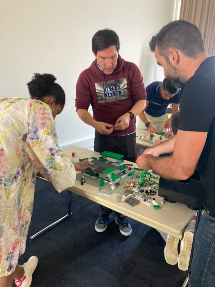 LEGO challenge half-dag Brussel teams bouwen aan tafels in moderne zaal · INNOV'events