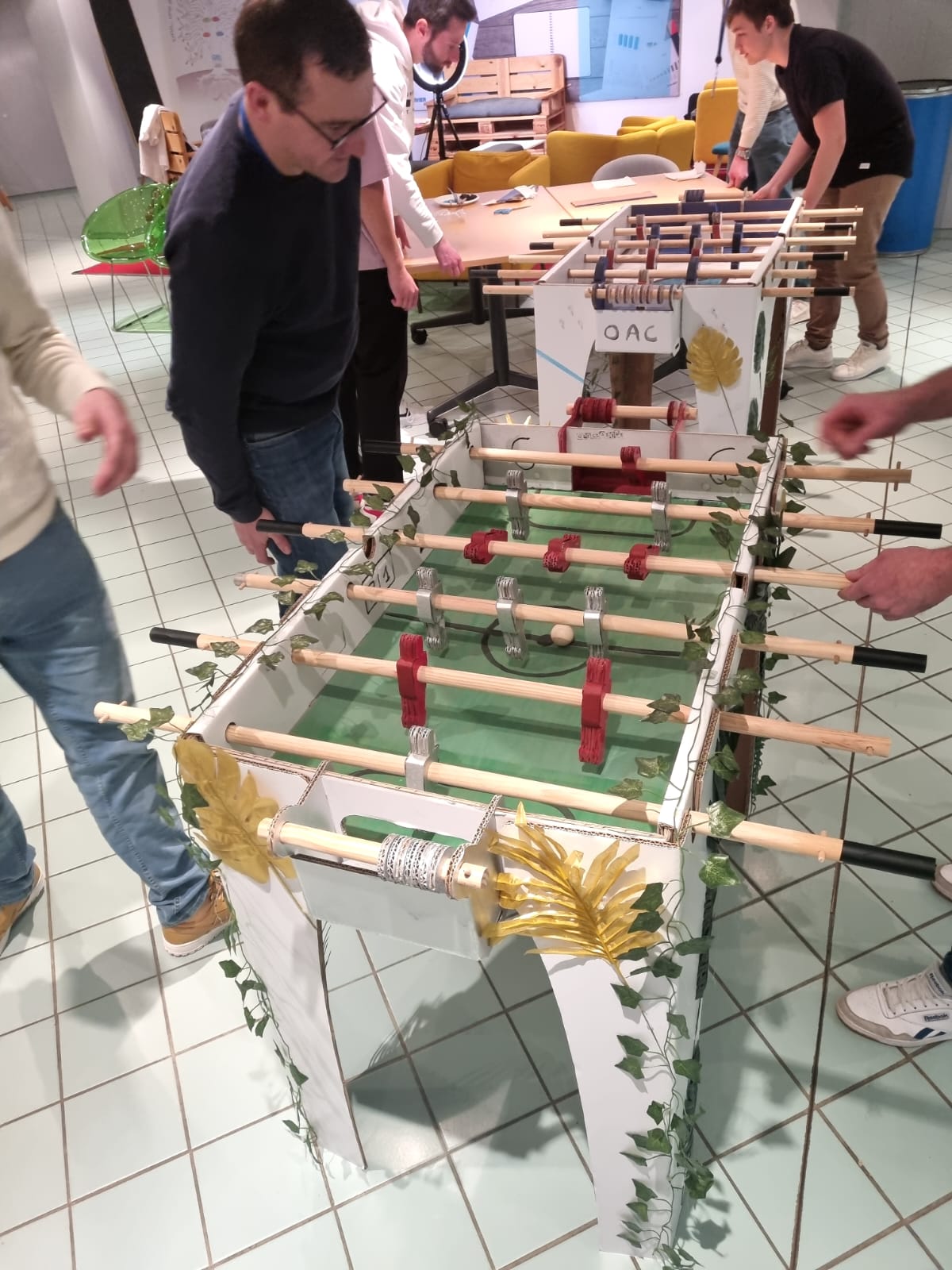 Création de baby-foot entreprise Liège soirée équipes posant avec leur table · INNOV'events