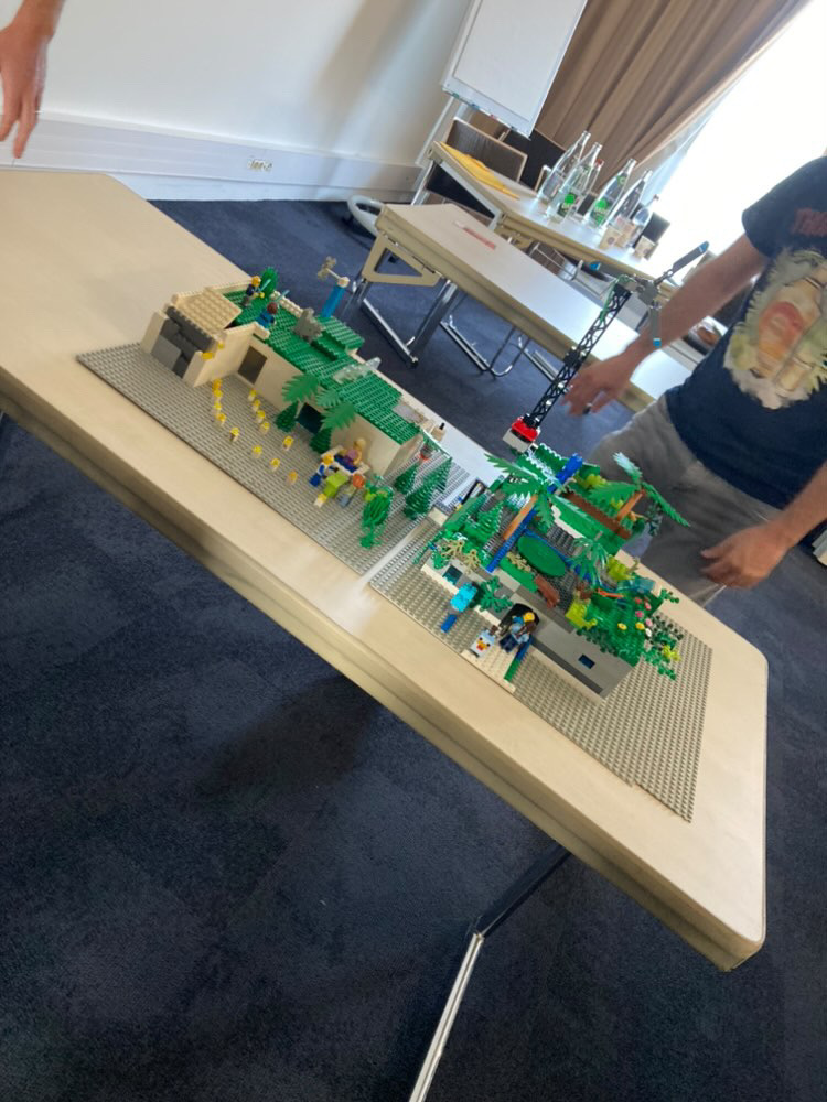 LEGO challenge avondformule Brussel deelnemers staand rond bouwtafel met drankje · INNOV'events