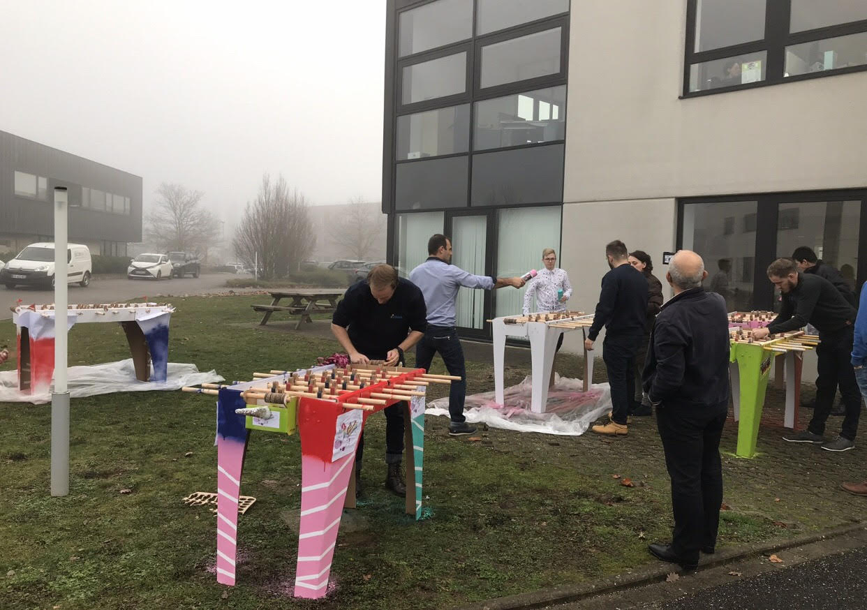 Teamactiviteit babyfoot bouw Luik deelnemers buiten aan Maasoevers · INNOV'events